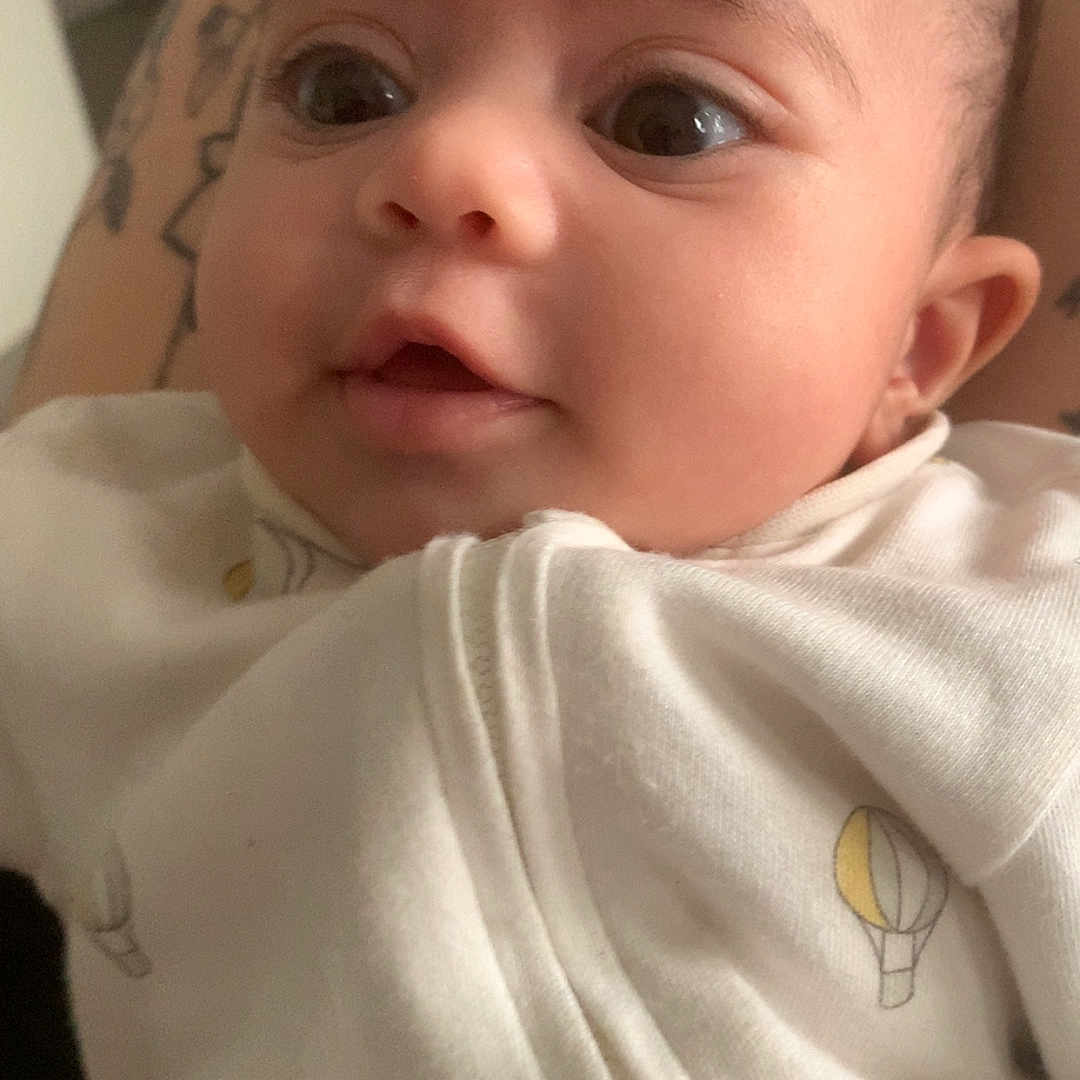 Djenecy a rejoint le concours — aidez-le/la à gagner de superbes lots ! adorable, baby, child, close_up, cozy, cute, eyes, face, hot_air_balloon_print, human, indoor, infant, mouth, newborn, person, portrait, skin, soft_light, tattoo, white_clothing