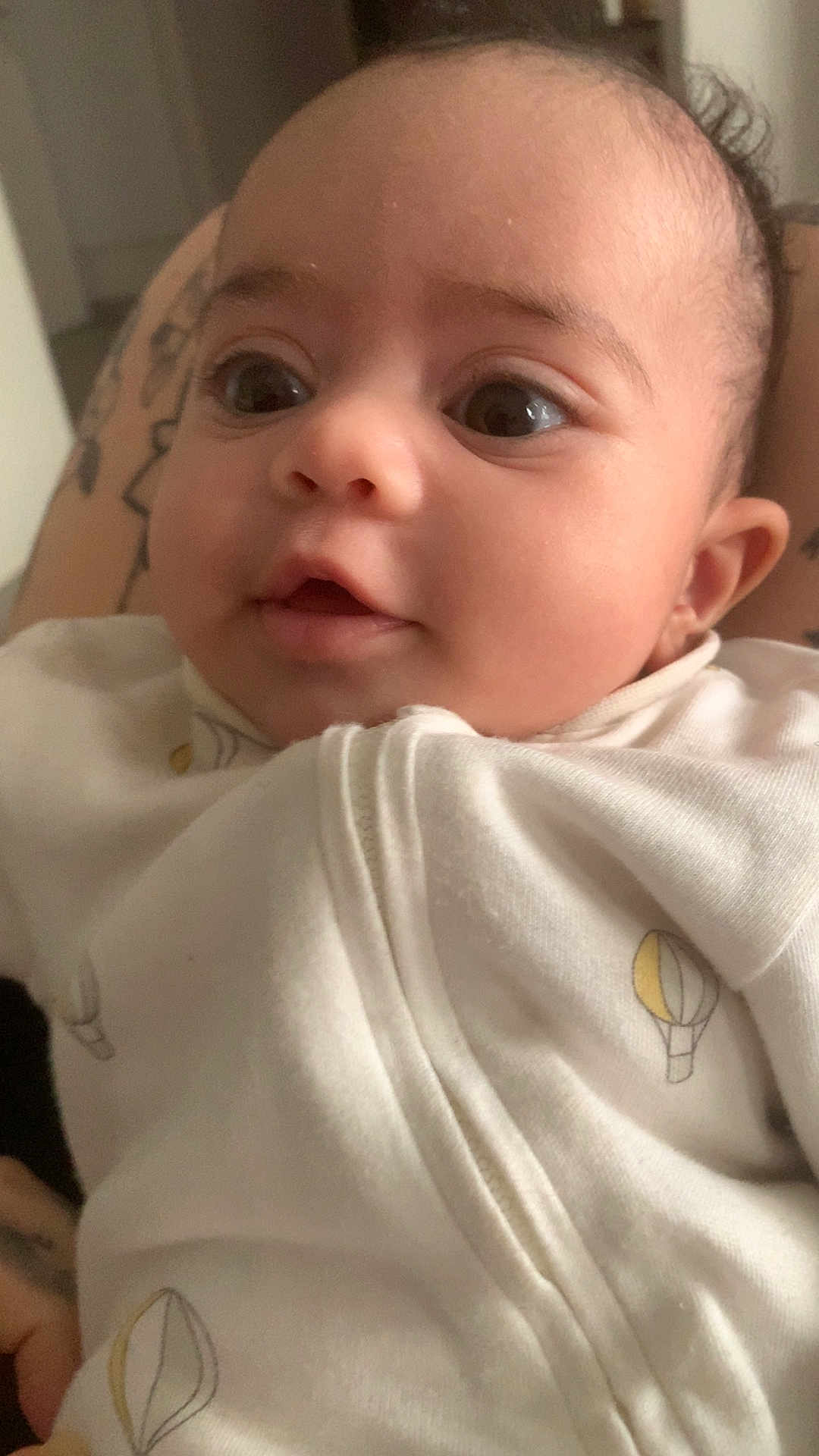 Djenecy a rejoint le concours — aidez-le/la à gagner de superbes lots ! adorable, baby, child, close_up, cozy, cute, eyes, face, hot_air_balloon_print, human, indoor, infant, mouth, newborn, person, portrait, skin, soft_light, tattoo, white_clothing