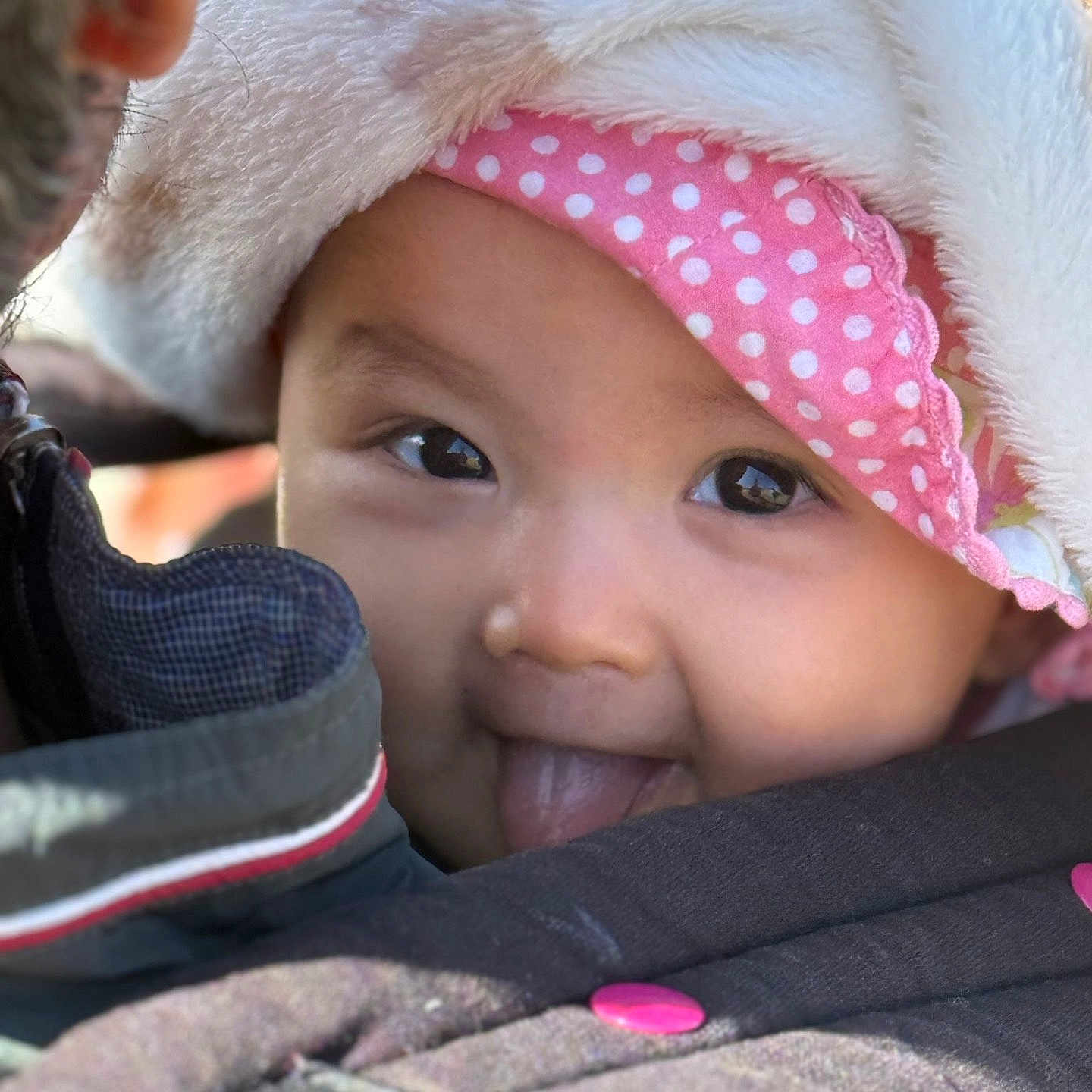 Katy participe au concours pour gagner de l'argent avec cette photo : baby, child, face, tongue_out, hood, pink_headband, polka_dot, closeup, cute, warm_clothing, jacket, outdoor, smiling, infant, person, babywearing, soft_texture, eyeshine, playful, portrait