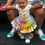 Mi'Chylah is registered to the contest to win money with this photo: toddler, child, smiling, braided_hair, bows, colorful_clothing, tutu_skirt, sneakers, adult_hands, indoor, carpet, party, celebration, holding_hands, happy, person, casual, accessories, joyful, young_child