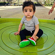 Vyom joined the competition — help win amazing prizes! toddler, child, playground, green, shoes, sitting, outdoor, curious, person, hand, casual_clothing, short_sleeve, pants, daylight, fence, background, park, young_child, expression, play