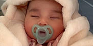 Amira joined the competition — help win amazing prizes! baby, pacifier, blanket, hood, sleeping, infant, pink_clothing, hand, cozy, soft_texture, indoor, child, cute, peaceful, person, portrait, warm, rest, comfort, nursery