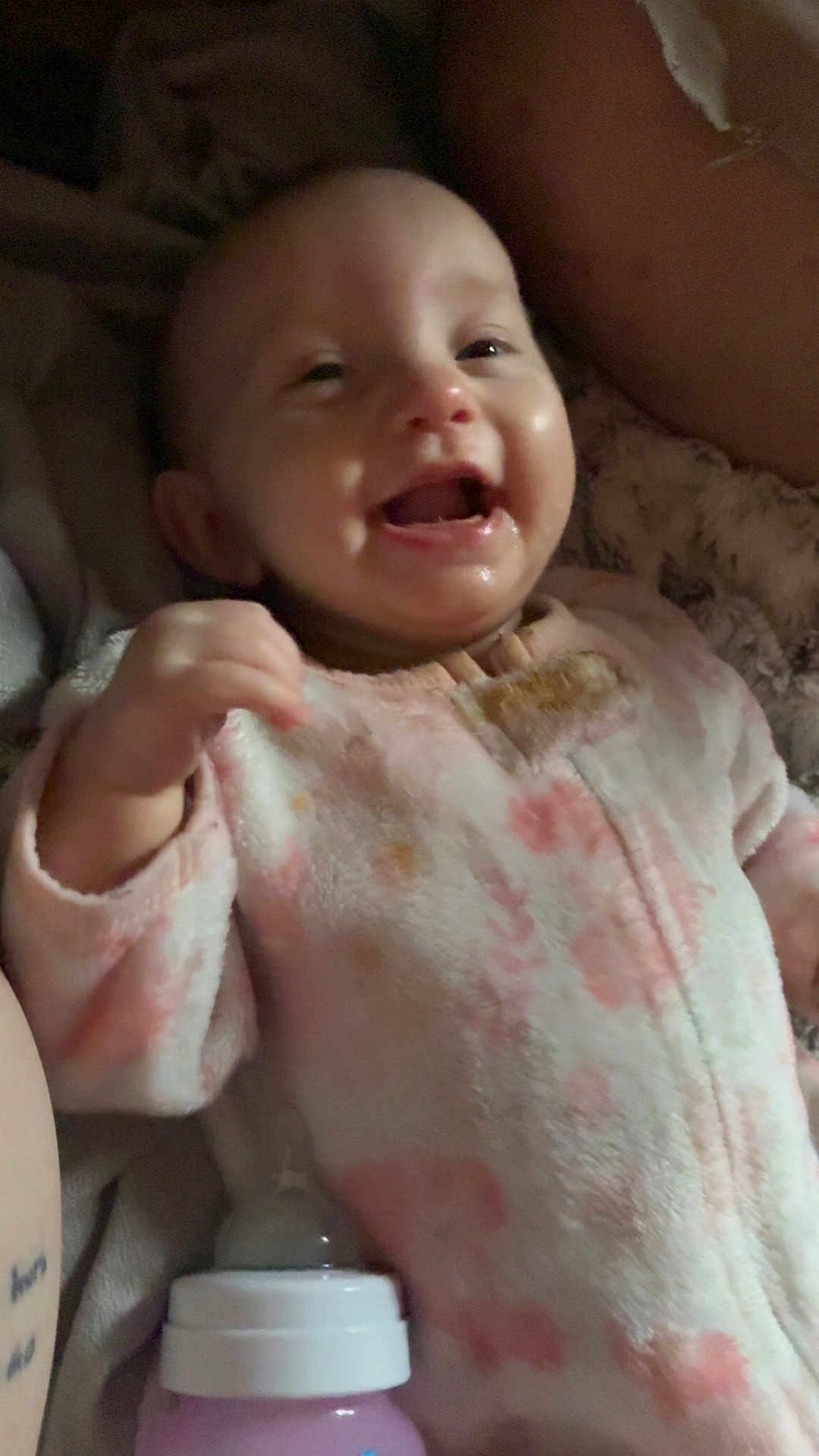 Winter is registered to the contest to win money with this photo: baby, infant, smiling, onesie, bottle, blanket, happy, child, cute, sleepwear, person, indoors, face, mouth_open, hand, soft, pink, cozy, lying_down, young