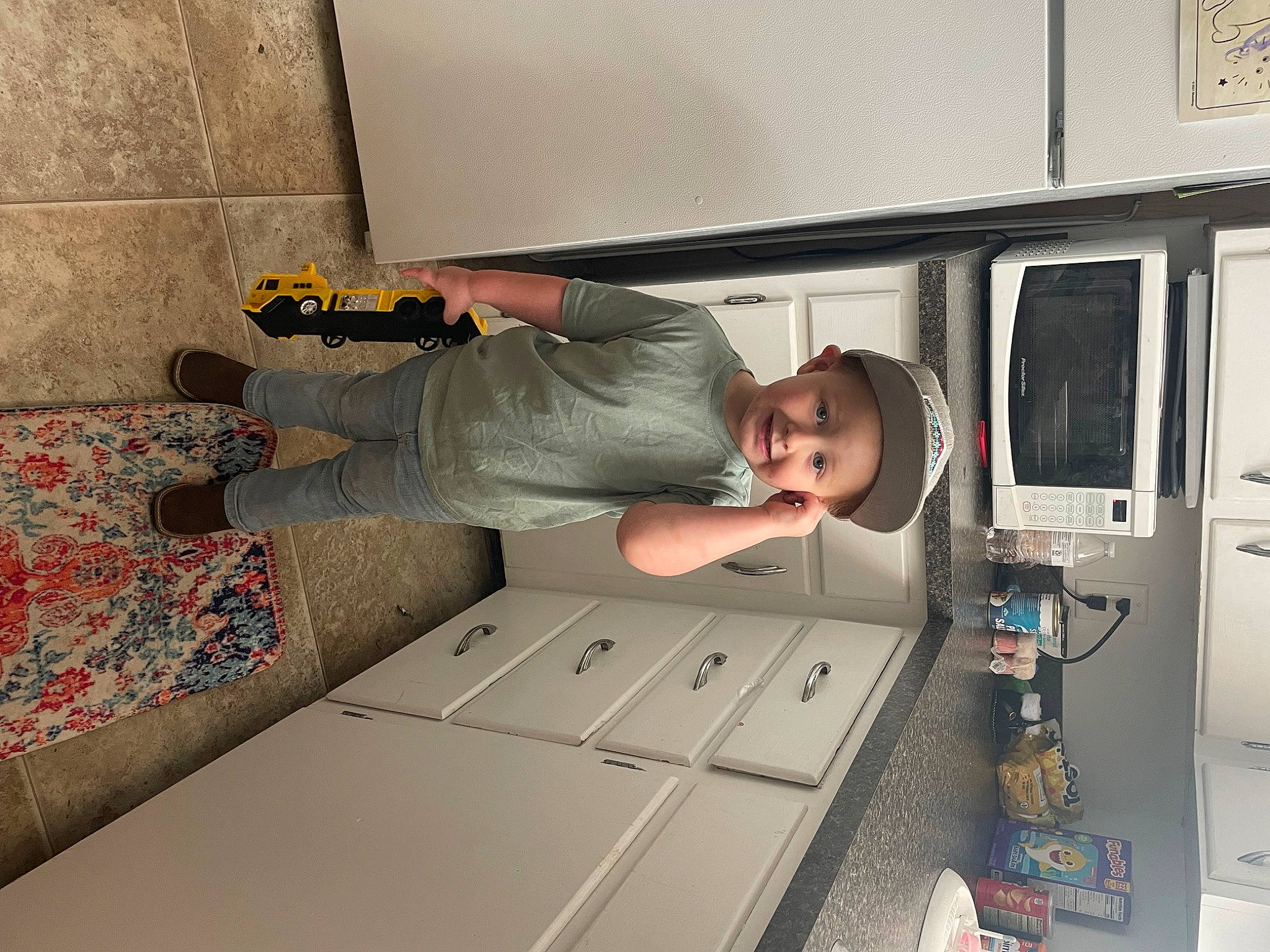 Dalen is registered to the contest to win money with this photo: comfort, flooring, flower, headwear, human_leg, joy, kitchen, machine, person, plant, room, smile, t_shirt, table, toddler