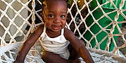 Cali is registered to the contest to win money with this photo: toddler, child, smiling, hammock_chair, outdoor, hair_bows, white_clothing, woven, garden, plant, fence, happy, sitting, cute, person, baby, portrait, daylight, backyard, fun