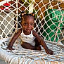 toddler, child, smiling, hammock_chair, outdoor, hair_bows, white_clothing, woven, garden, plant, fence, happy, sitting, cute, person, baby, portrait, daylight, backyard, fun