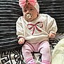 baby, infant, pacifier, headband, pink_bow, white_sweater, pink_pants, socks, couch, blanket, texture, cozy, cute, child, portrait, indoors, clothing, soft, relaxed, smiling