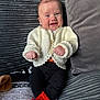 Mekltiè-Lee is registered to the contest to win money with this photo: baby, smiling, infant, cozy, knitted_sweater, red_socks, couch, gray, texture, cute, happy, child, indoor, portrait, person, furniture, comfortable, seated, warm_clothing, small_hands
