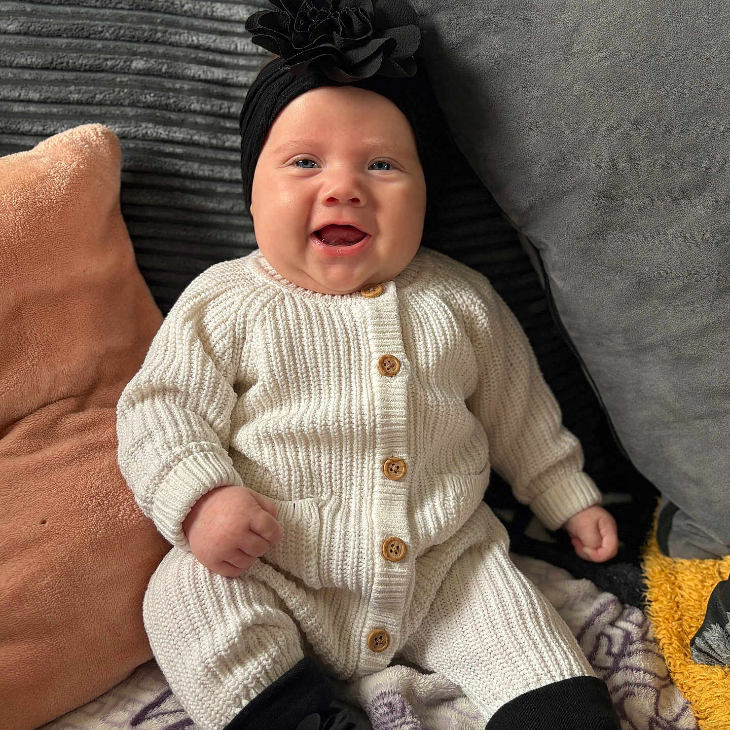 Mekltiè-Lee joined the competition — help win amazing prizes! baby, black_booties, blanket, child, comfort, cozy, cushion, cute, flower, happy, headband, home, indoors, infant, knitwear, portrait, sitting, smiling, soft_texture, wooden_buttons