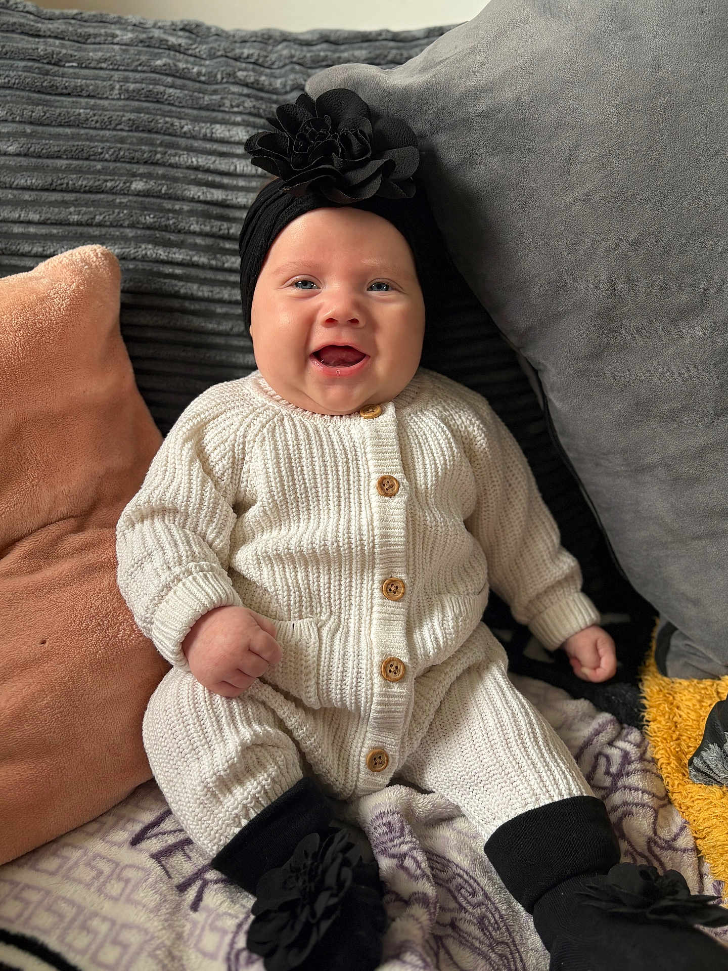 Mekltiè-Lee joined the competition — help win amazing prizes! baby, smiling, knitwear, headband, flower, cushion, blanket, cozy, sitting, indoors, cute, child, comfort, portrait, happy, wooden_buttons, black_booties, soft_texture, home, infant