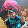 adult_hand, baby, child, close_up, costume, feathers, hand, high_chair, indoor, pirate_hat, playful, portrait, skull_and_crossbones, smiling, striped_shirt, sunlight, table, toddler, waving, window