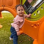 toddler, child, playground, outdoor, smiling, jeans, pink_sweater, grass, play_structure, curly_hair, happy, casual_clothing, daylight, active, cute, young_child, person, fun, exploring, leaves