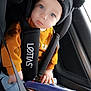 baby, infant, car_seat, beanie, pom_poms, blue_eyes, toy_steering_wheel, seat_belt, sweater, jeans, car_interior, window, hand, close_up, portrait, child, cute, travel, safety, candid