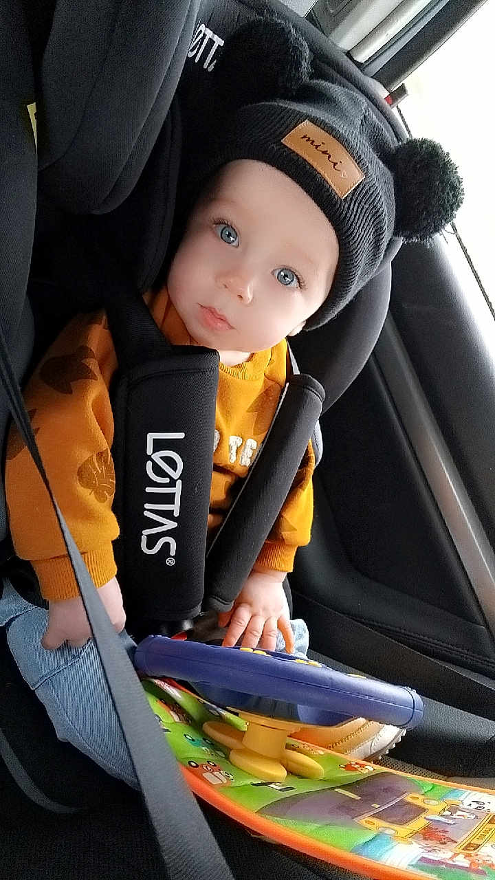 Eden a rejoint le concours — aidez-le/la à gagner de superbes lots ! baby, infant, car_seat, beanie, pom_poms, blue_eyes, toy_steering_wheel, seat_belt, sweater, jeans, car_interior, window, hand, close_up, portrait, child, cute, travel, safety, candid