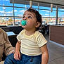 Benício joined the competition — help win amazing prizes! child, toddler, pacifier, indoor, restaurant, window, blue_sky, curly_hair, striped_shirt, denim_pants, sitting, table, gaze_up, lights, ceiling, person, cute, casual_clothing, hand, portrait