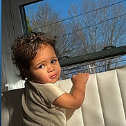 Benício joined the competition — help win amazing prizes! child, toddler, baby, face, curly_hair, onesie, window, sunlight, shadow, indoor, upholstery, looking_back, portrait, cheeks, expression, arm, hand, daylight, home, seat