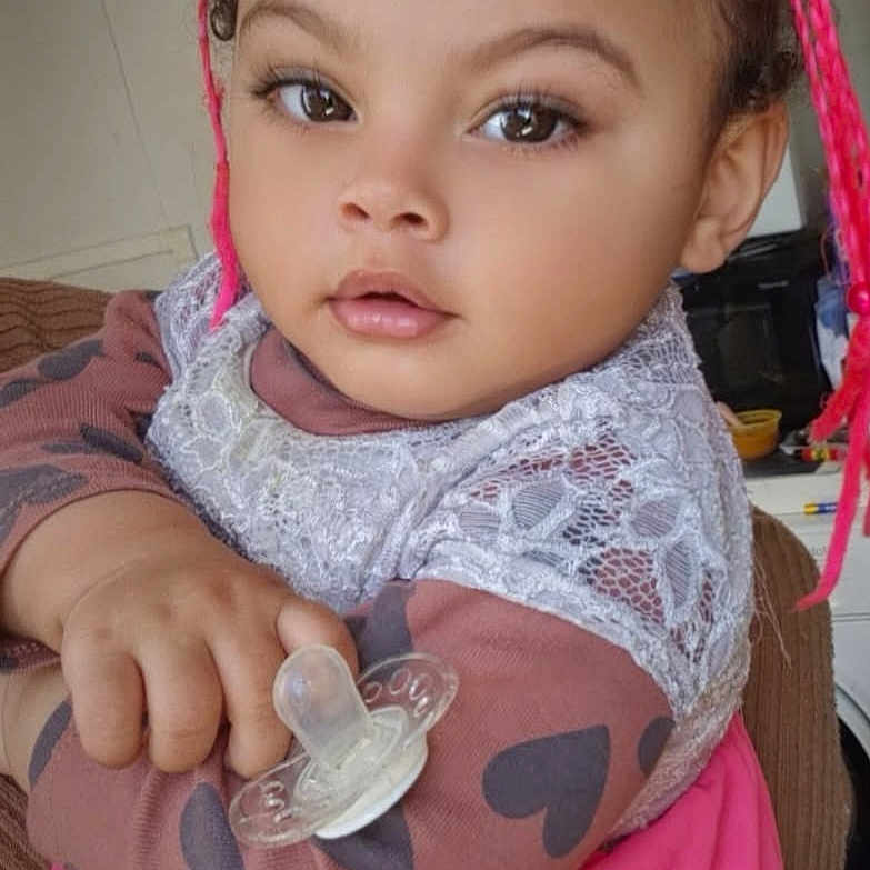 Nihya participe au concours pour gagner de l'argent avec cette photo : baby, braids, child, closeup, clothing, cute, expression, face, furniture, hand, holding, home, indoor, lace, pacifier, person, pink, portrait, sitting, toddler