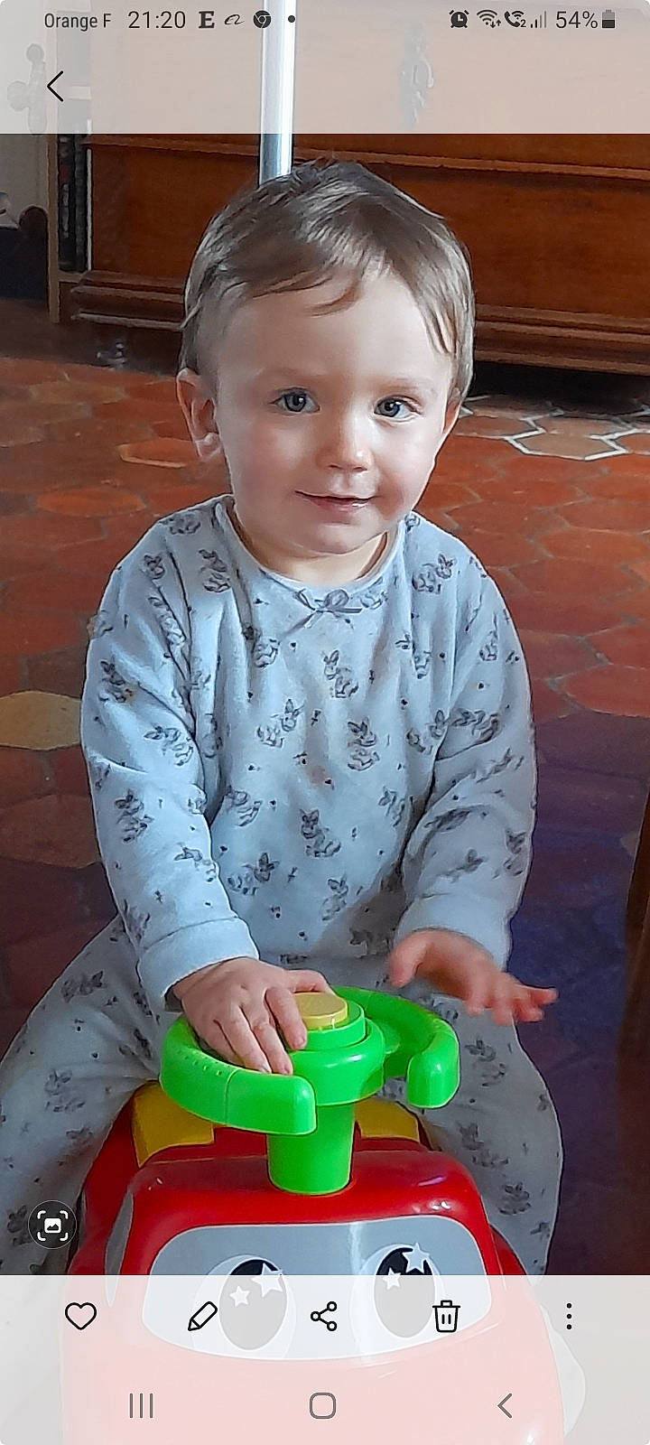 Gabin participe au concours pour gagner de l'argent avec cette photo : arm, baby_playing_with_toys, baby_toddler_clothing, cheek, child, flooring, fun, hair, hardwood, head, joy, organ, person, photograph, sitting, sleeve, snapshot, standing, t_shirt, toddler