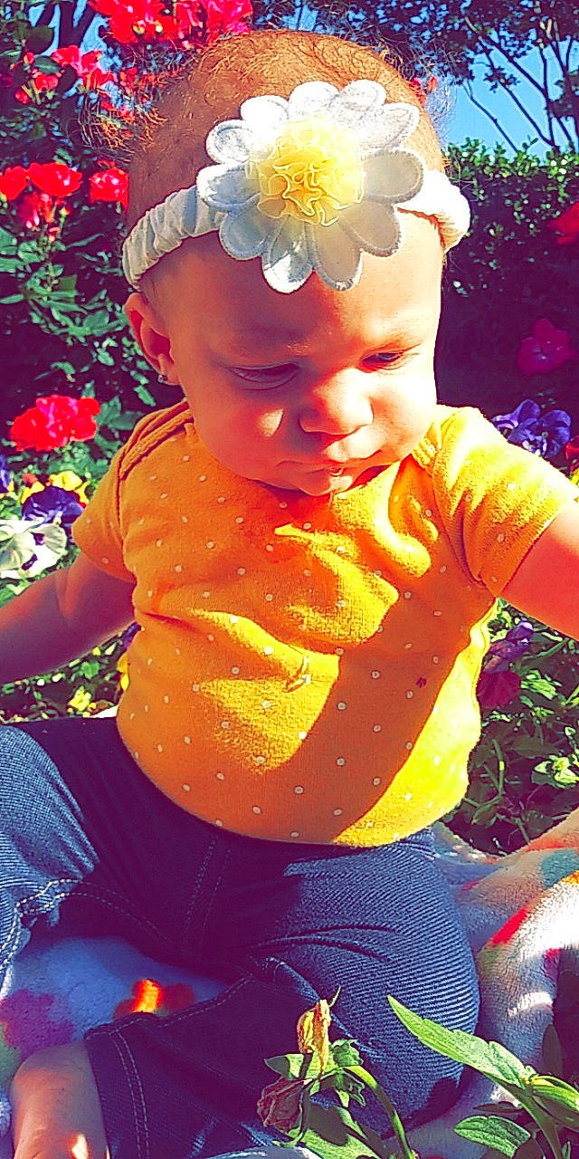 Emelia is registered to the contest to win money with this photo: abdomen, child, fashion_accessory, flower, fun, hair_accessory, happy, perennial_plant, person, petal, pink, plant, play, red, smile, summer, sunlight, toddler, yellow