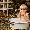 David is registered to the contest to win money with this photo: baby, child, outdoor, basin, milk_bath, orange_slice, fruit, nature, fence, greenery, curious, innocent, summer, sitting, water, cute, portrait, skin, toddler, playful