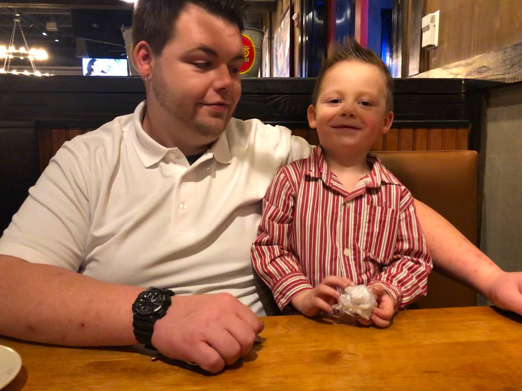 Grayson is registered to the contest to win money with this photo: chair, child, dress, event, finger, flooring, fun, hand, happy, hardwood, joy, leisure, person, sitting, smile, table, tableware, toddler, varnish, watch