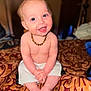 baby, child, smiling, blue_eyes, mohawk, necklace, bare_chest, sitting, bedspread, patterned_fabric, indoor, happy, cute, infant, portrait, person, skin, feet, hands, shorts