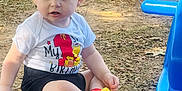 Coulson is registered to the contest to win money with this photo: toddler, child, outdoor, birthday, shirt, shorts, yellow_shoes, grass, leaves, playground, blue_slide, sitting, hairstyle, curious, daylight, park, person, young_child, casual, ground