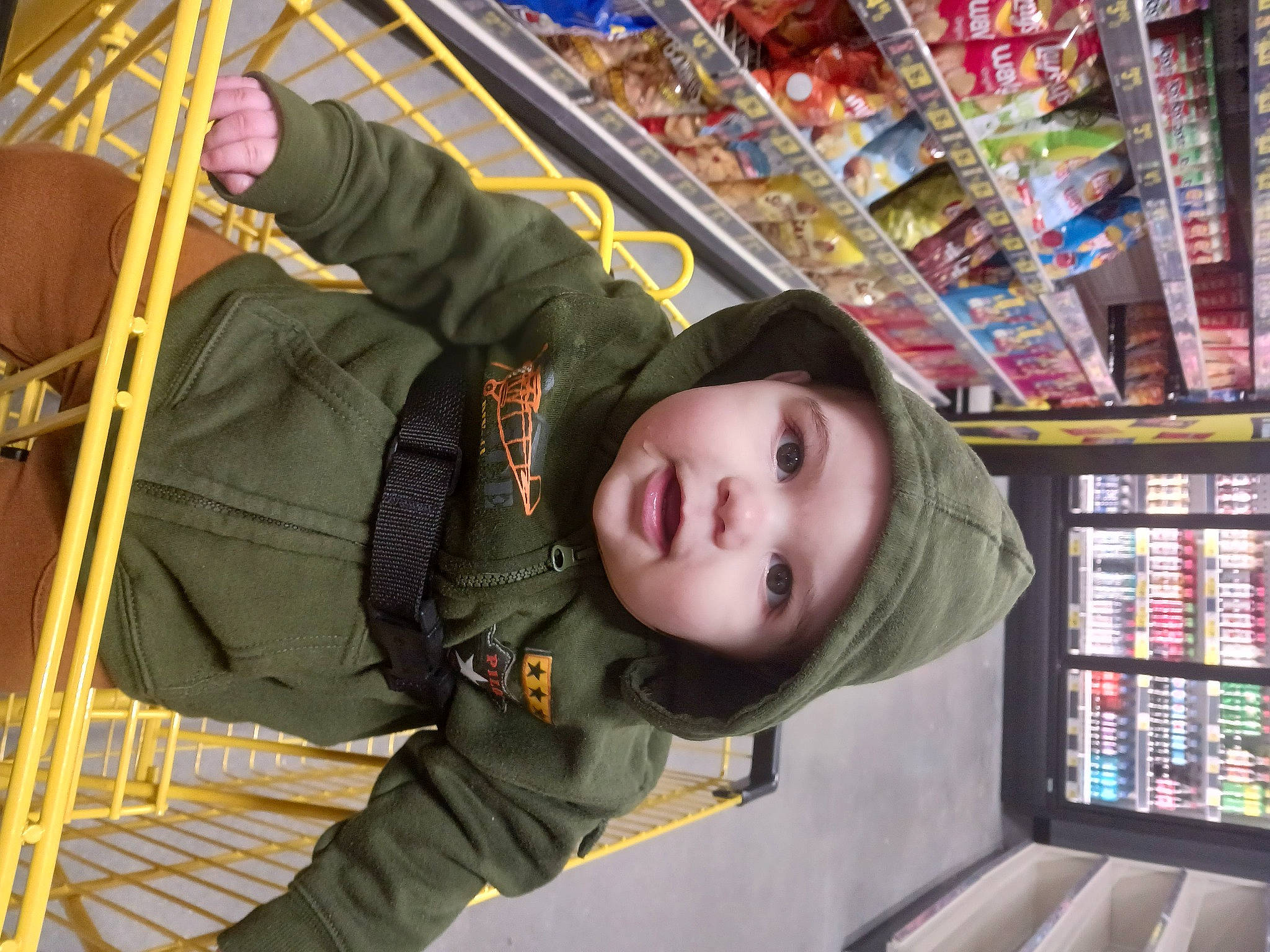 Lucas is registered to the contest to win money with this photo: baby, building, child, city, convenience_store, fun, headwear, hoodie, jacket, leisure, person, public_space, publication, retail, service, shelf, shelving, snapshot, toddler, tree