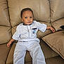 Sokowonchin is registered to the contest to win money with this photo: toddler, child, couch, sofa, clothing, light_blue, police_car_patch, sitting, indoors, furniture, young_child, barefoot, casual, relaxed, person, portrait, home, comfortable, curious, face