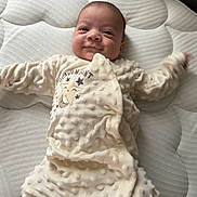 Atticus is registered to the contest to win money with this photo: baby, infant, smile, onesie, sleepwear, mattress, texture, lying_down, cute, child, soft, sleep, comfort, happy, face, person, bedroom, cozy, newborn, apparel