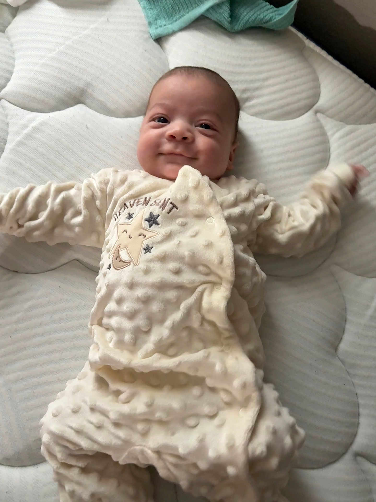 Atticus is registered to the contest to win money with this photo: baby, infant, smile, onesie, sleepwear, mattress, texture, lying_down, cute, child, soft, sleep, comfort, happy, face, person, bedroom, cozy, newborn, apparel