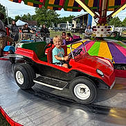 Huxton joined the competition — help win amazing prizes! child, carnival, ride, mini_car, red, smile, outdoor, amusement_park, people, colorful, canopy, fun, summer, festival, happy, vehicle, toy_car, family, daytime, park