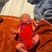 Raelynn joined the competition — help win amazing prizes! newborn, baby, infant, red_onesie, blanket, orange_blanket, blue_blanket, gray_blanket, sleeping, smiling, peaceful, sunlight, indoors, soft_texture, cozy, cute, skin, hand, foot, lying_down