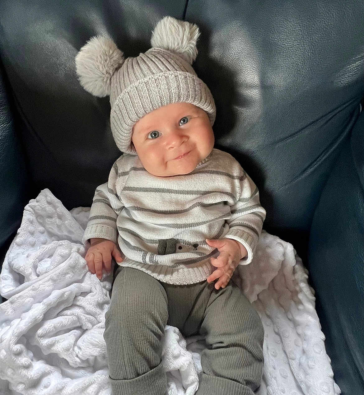 Coby joined the competition — help win amazing prizes! baby, child, smile, hat, pom_poms, striped_clothing, blanket, leather_chair, cozy, cute, infant, portrait, sitting, soft_texture, warm_clothing, happy, indoors, person, young_child, knit_hat
