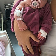 Alma a rejoint le concours — aidez-le/la à gagner de superbes lots ! baby, infant, pacifier, hospital, medical_tube, bandage, sleeping, purple_clothing, adult_hand, indoor, window, blanket, care, healthcare, person, newborn, resting, closeup, treatment, comfort