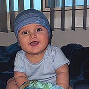 Matthias -Alexander joined the competition — help win amazing prizes! baby, infant, blue_beanie, smiling, plush_toy, bed, blanket, window, vertical_blinds, indoor, child, cute, happy, portrait, person, clothing, soft_toy, seated, home, young_child