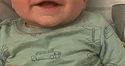 John Thomas joined the competition — help win amazing prizes! airplane_pattern, baby, blanket, child, close_up, clothing, couch, eyes, face, happy, home, indoors, infant, onesie, pajamas, portrait, reclining, sitting, smiling, vehicle_pattern