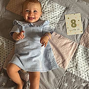 Albane participe au concours pour gagner de l'argent avec cette photo : baby, infant, child, smiling, striped_dress, blue_eyes, patchwork_quilt, star_pattern, pastel_colors, barefoot, card, 8_months_old, cute, happy, lying_down, soft_lighting, playful, ruffled_collar, bracelet, indoor