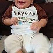 Angel is registered to the contest to win money with this photo: baby, child, smiling, happy, sitting, portrait, indoors, cushion, chair, clothing, shirt, pants, socks, face, hands, feet, infant, lifestyle, close_up, photography