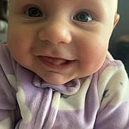 Lenora joined the competition — help win amazing prizes! apparel, baby, child, closeup, cute, expression, face, happy, indoors, infant, onesie, person, portrait, purple, skin, smile, soft, warm, white, young