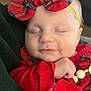 baby, sleeping, red_clothing, headband, plaid, bow, infant, closeup, hand, smile, cute, child, soft, cozy, portrait, peaceful, indoors, person, face, resting