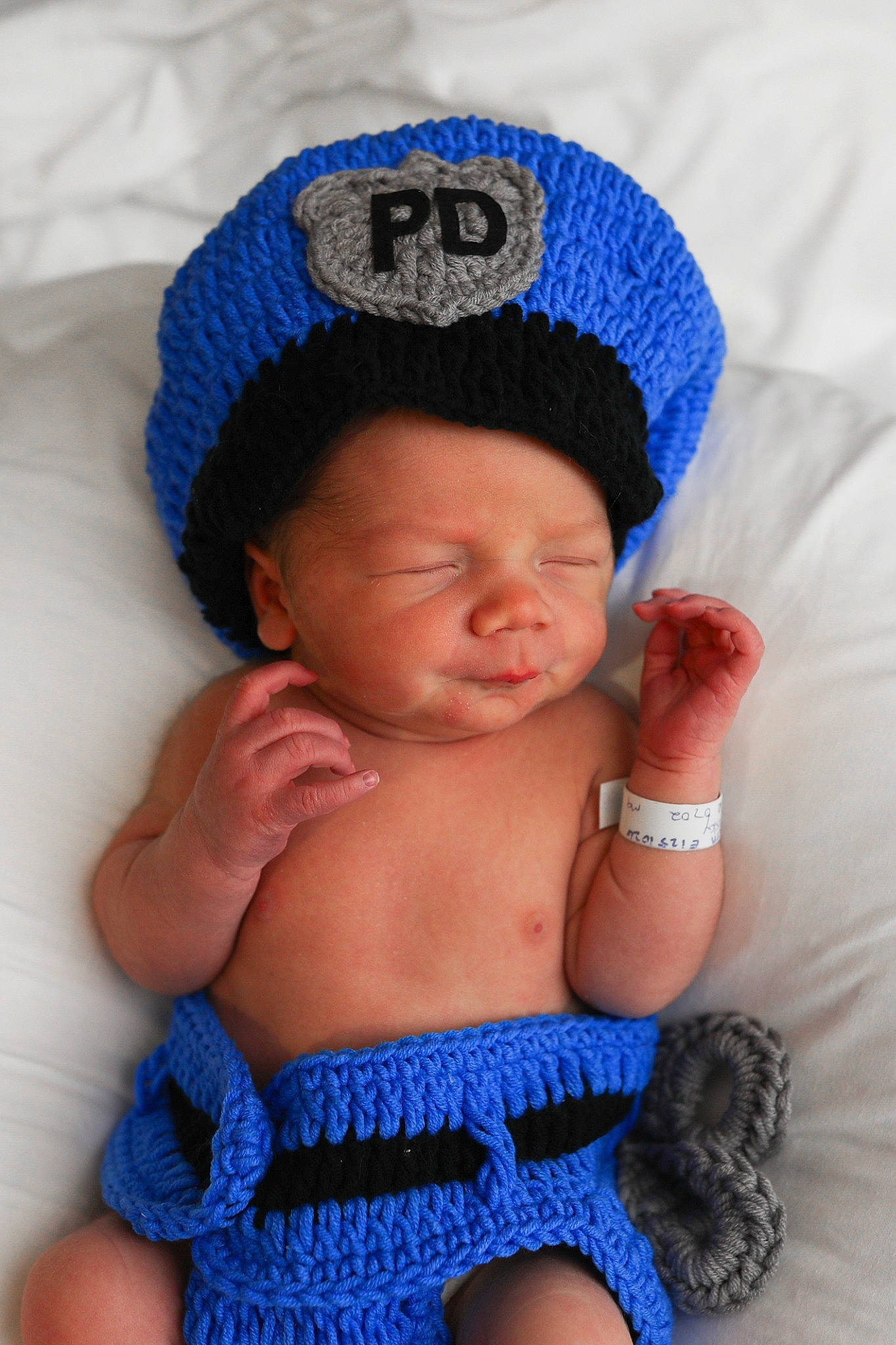 Braylen is registered to the contest to win money with this photo: abdomen, arm, azure, baby, baby_sleeping, baby_toddler_clothing, blue, cap, eye, face, finger, hand, head, headgear, organ, person, pink, purple, skin, textile