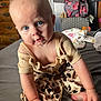 baby, blue_eyes, clothing, curious, bed, indoor, infant, leopard_print, person, portrait, sitting, skin, soft_lighting, top, young_child, hand, foot, furniture, room, casual