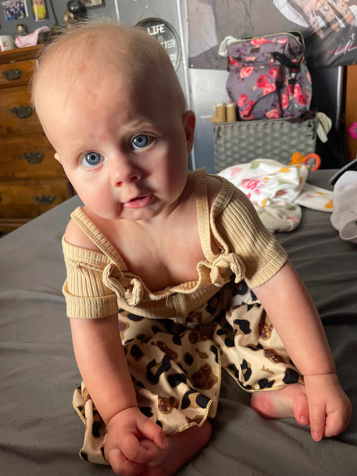 Huntleigh is registered to the contest to win money with this photo: baby, blue_eyes, clothing, curious, bed, indoor, infant, leopard_print, person, portrait, sitting, skin, soft_lighting, top, young_child, hand, foot, furniture, room, casual