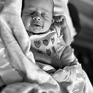 Huntleigh is registered to the contest to win money with this photo: baby, newborn, infant, sleeping, blanket, onesie, strawberry_pattern, black_and_white, close_up, portrait, peaceful, soft_texture, wrapped, cute, child, small_hands, cozy, resting, indoors, person