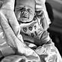 baby, newborn, infant, sleeping, blanket, onesie, strawberry_pattern, black_and_white, close_up, portrait, peaceful, soft_texture, wrapped, cute, child, small_hands, cozy, resting, indoors, person