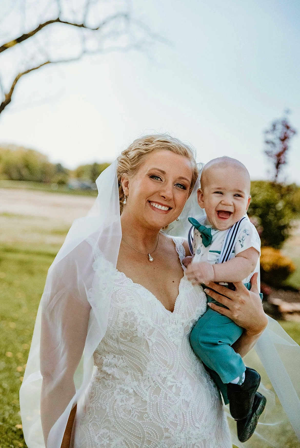 Elliot is registered to the contest to win money with this photo: bride, baby, wedding_dress, veil, outdoor, smile, happy, child, portrait, nature, grass, tree, person, celebration, event, holding, formal_wear, joy, family, daylight