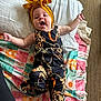 Kynslee joined the competition — help win amazing prizes! baby, child, headband, yellow_bow, black_outfit, patterned_clothing, blanket, colorful_blanket, text_on_blanket, happy, smiling, lying_down, carpet, indoors, cute, infant, person, fabric, playful, expression