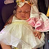 baby, infant, child, sleeping, portrait, car_seat, dress, white_dress, pink_clothing, bow, headband, blanket, cushion, harness, feet, shoes, indoor, close_up, sitting, sleepy
