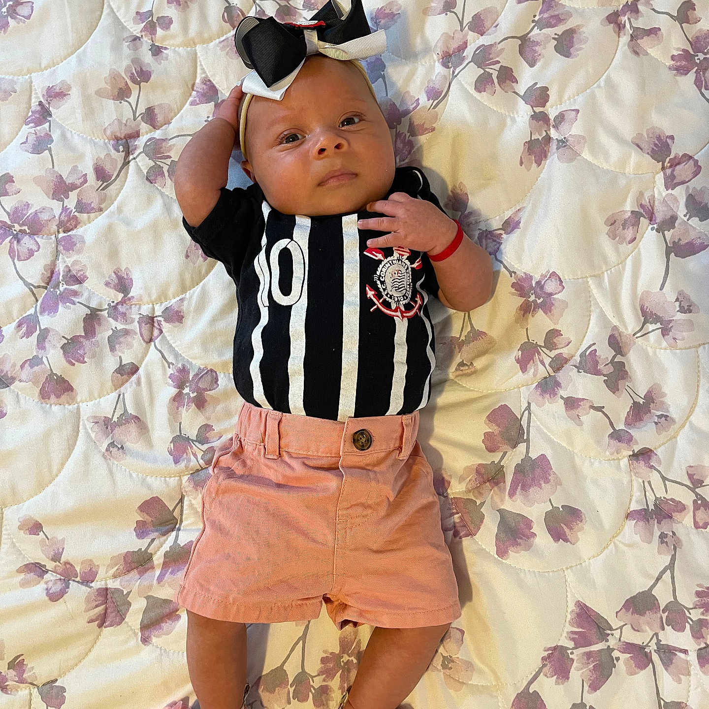Mary Rose joined the competition — help win amazing prizes! baby, infant, child, portrait, lying_down, floral_blanket, quilt, bow, hair_accessory, striped_shirt, shorts, sneakers, floral_shoes, fashion, cute, face, smiling, indoor, bedroom, photography
